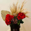 Red roses in a black hatbox with dried pampas grass and a small heart topper