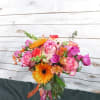 Colorful bouquet of pink roses and orange gerbera daisies in a glass vase