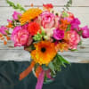 Bright mixed bouquet with pink roses and orange gerbera daisies in a glass vase