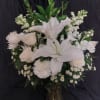 White lilies and roses arranged in a tall vase with greenery