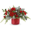 Red floral arrangement in a glittery red container with pinecones