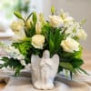 White roses and lilies arranged in a white angel vase