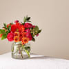 Bright orange and red bouquet in a clear glass vase