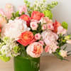 Pink and coral roses arranged in a green glass vase