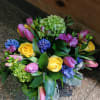Compact bouquet of yellow roses, pink tulips, green hydrangeas and purple-blue hyacinths.