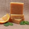 Stacked orange soap bars with an orange slice and mint leaves