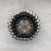 A circular ornament wreath with black, silver, and gold baubles and a star center