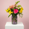 Pink rose and yellow mixed flowers in a glass vase