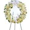 White floral wreath on a stand with a large white ribbon bow