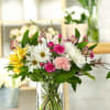 Mixed bouquet of daisies, carnations, and alstroemeria in a clear glass vase