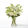 White lilies and roses arranged in a clear glass vase