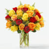 Bouquet of red, yellow, and orange roses in a clear glass vase