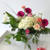 A silver footed vase with hydrangea tulips ranunculus gerber daisies and roses