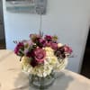 Pink roses and white hydrangeas in a glass vase with a heart pick