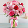 Pink and red mixed bouquet in a glass vase with a pink ribbon