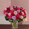 Bouquet of pink, red, and lavender roses in a clear glass vase