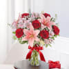 Bouquet of red roses and pink lilies in a glass vase with a red ribbon