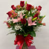 Bouquet of red roses and pink lilies in a glass vase with a red ribbon