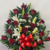 Basket arrangement of red roses and white lilies with a red bow