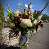 Large bouquet of red and white flowers in a glass vase with a white ribbon