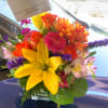 Bright mixed bouquet in a glass vase with yellow lilies and orange flowers