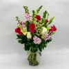 Bouquet of red roses, lilies, and pink flowers in a glass vase