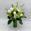 White roses and green blooms in a clear glass vase