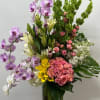 Tall mixed bouquet with orchids, roses, lilies, and hydrangeas in a glass vase