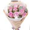 Pale pink roses gathered in a tight, rounded hand-tied bouquet create a