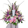 Large pink and purple floral arrangement in a white pedestal vase