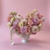 Pink and white flower arrangement in a white pedestal vase