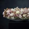 Low floral arrangement of blush and white roses with orchids in a dark bowl