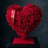 Heart-shaped arrangement of red roses on a red base