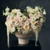 Large pastel floral arrangement in a beige pedestal vase