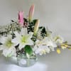 White lilies and pink buds arranged in a clear glass vase