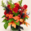 Autumn bouquet of red and orange flowers in a glass vase with black ribbon