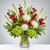 Red roses and white blooms in a clear glass vase with green hydrangeas