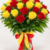 Bouquet of red and yellow roses in a clear glass vase with a red and yellow ribbon