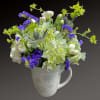 White and purple flowers arranged in a snowflake mug vase