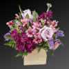 Pink and purple mixed flower arrangement in a beige vase