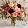 Mixed pink and burgundy flower arrangement in a clear glass vase