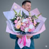 A lush bouquet of mixed flowers wrapped with peony-inspired accents-this large hand-tied