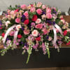Large pink and purple floral casket spray with ribbon streamers