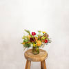 Mixed bouquet in a glass jar on a wooden stool