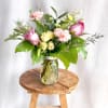 Pink and yellow roses with carnations in a glass jar vase