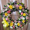 Large floral wreath with yellow roses, pink flowers, and a yellow ribbon