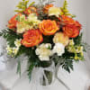 Bouquet of orange roses and pale carnations in a glass vase