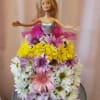Doll in a dress covered with pastel daisies and ribbon