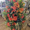 Large standing floral spray with orange roses and alstroemeria on an easel