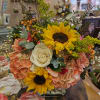 Bouquet with sunflowers, white roses, and peach hydrangeas in a glass vase